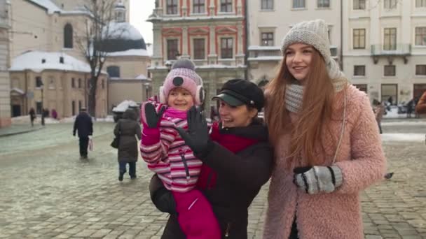 Zwei junge lächelnde Touristinnen mit Adoptivkind spazieren an berühmten Sehenswürdigkeiten der Altstadt — Stockvideo