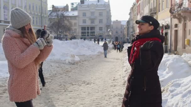 Två unga leende kvinnor turister bloggare tar bilder porträtt på mobiltelefon på stadens gata — Stockvideo