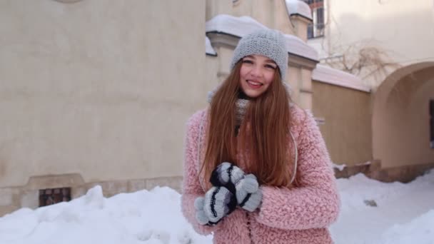 Καυκάσια νεαρή γυναίκα χαμογελά στην κάμερα, που δείχνει το σήμα της καρδιάς, ενώ στέκεται έξω στη χειμερινή πόλη — Αρχείο Βίντεο