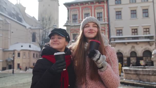 Två leende kvinnor turister reser tillsammans, dricka varmt te, kaffe från koppar på stadens gata — Stockvideo