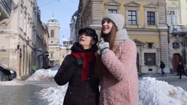 Δύο χαμογελαστές γυναίκες τουρίστες περπατούν μαζί στο δρόμο της πόλης, οικογενειακό ζευγάρι μιλάει, αγκαλιάζει — Αρχείο Βίντεο