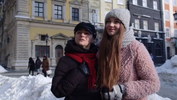 Två leende kvinnor systrar turister går tillsammans på stadens gata, familj par pratar, omfamna — Stockvideo