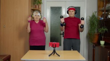 Yaşlı yaşlı çift büyükanne büyükbaba halterlerle egzersiz yapıyor, spor yapıyor.