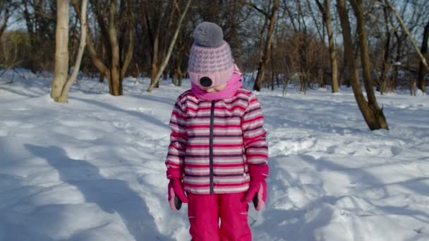 Child girl looking at camera, starting laughing, fooling around, smiling in winter snow park forest — Stock Video