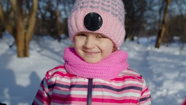 Χαμογελώντας ντροπαλό παιδί κοιτάζοντας κάμερα, χαζεύοντας τριγύρω, κάνοντας γκριμάτσες στο χειμερινό χιονισμένο δάσος — Αρχείο Βίντεο