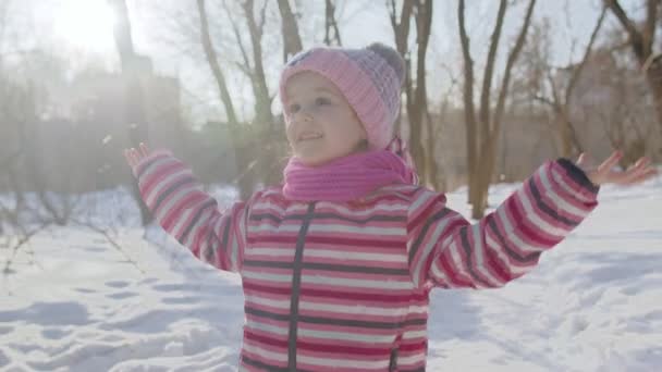 冬の日当たりの良い公園の森の雪の道を歩く陽気な子供の女の子、クリスマス休暇旅行 — ストック動画