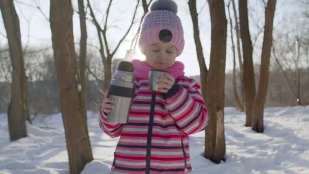 Portrét roztomilé usměvavé dítě dívka dítě cestovatel chůze, pití horký nápoj čaj v zimním parku — Stock video