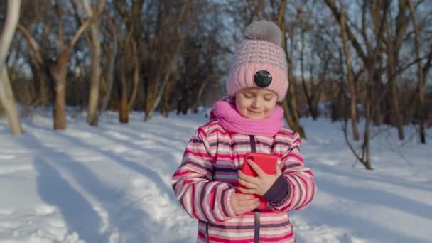 Παιδί blogger κορίτσι κάνει βιντεοκλήση στο κινητό τηλέφωνο, selfie φωτογραφία για κοινωνικά δίκτυα στο χειμερινό πάρκο — Αρχείο Βίντεο