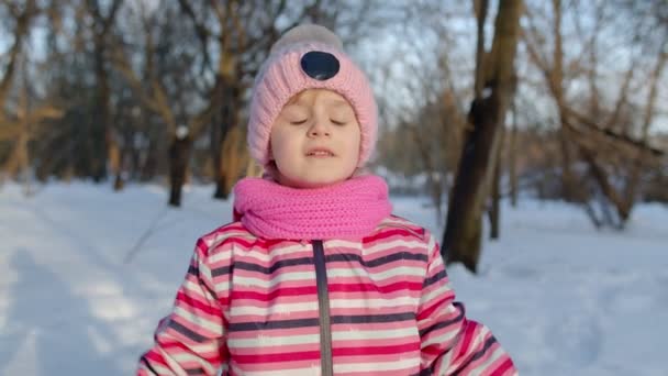 冬の公園の森の雪に覆われた道を歩きながら、楽しく踊り、楽しい子供が走っています。 — ストック動画