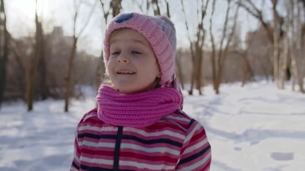 Criança sorridente menina turista andando, se divertindo na estrada nevada no inverno ensolarado parque floresta, pôr do sol — Vídeo de Stock