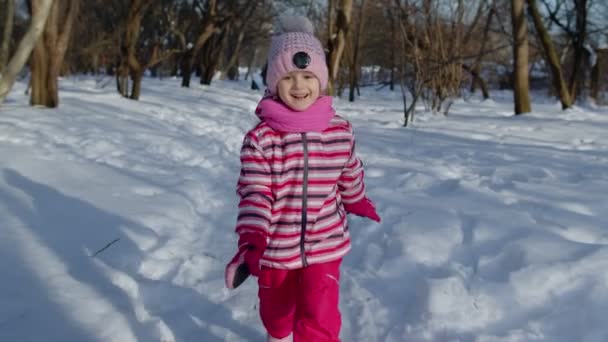 Усміхнений дитина біжить, розважається, танцює, обманює на засніженій дорозі в зимовому парку ліс — стокове відео