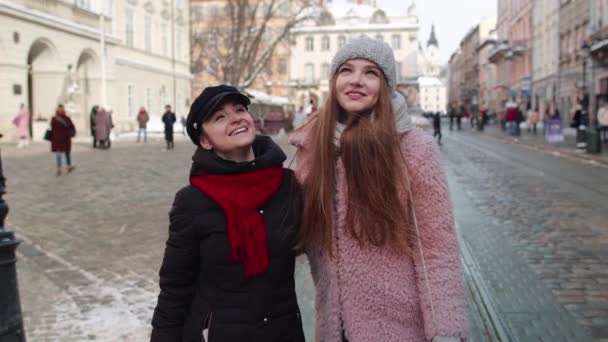 Két mosolygó nő nővérek turisták együtt sétálnak a város utcáján, fiatal pár beszél, ölelkeznek — Stock videók