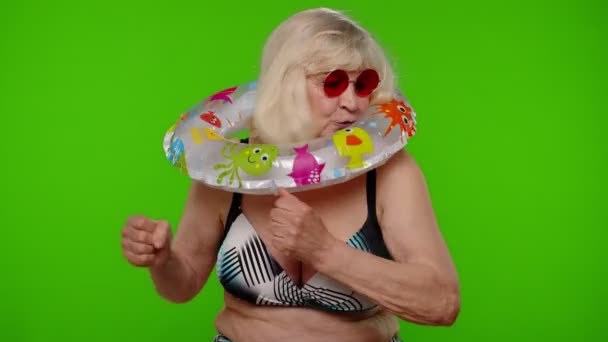 Volwassen vrouw reiziger dansen, vieren, poseren met rubber ring in badpak beha op chroma sleutel — Stockvideo