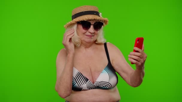 Olgun kadın gezgin blogcu güneş gözlüklü, selfie portresi fotoğrafı çeken, akıllı telefondan video görüşmesi yapan. — Stok video
