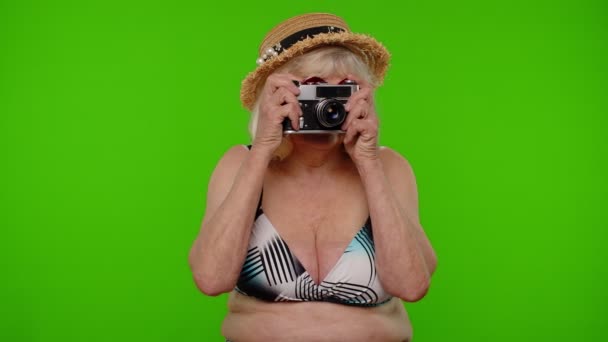 Senior vrouw toeristische fotograaf in badpak het nemen van foto 's op retro camera, glimlachen op chroma sleutel — Stockvideo