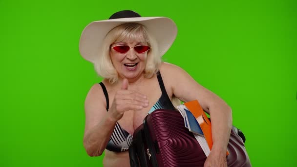 Senior woman tourist in swimsuit with luggage, passport, tickets asking to follow join on chroma key — Stock Video