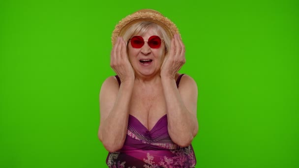 穿着泳衣的有趣而有趣的老年女性游客，鬼鬼祟祟地做着愚蠢的无头脑的表情 — 图库视频影像