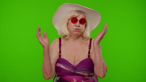 Funny silly senior woman tourist in swimsuit, fooling around making stupid brainless expressions — Stock Video