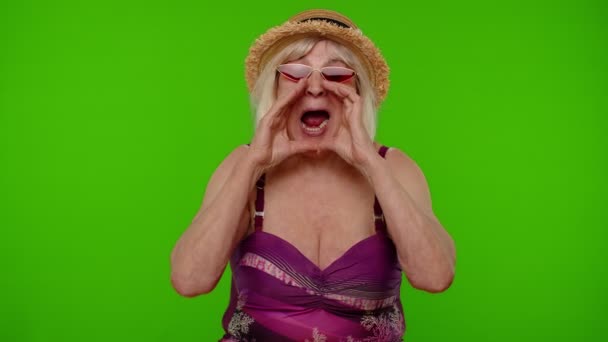 Senior kvinna turist i baddräkt, röda solglasögon och hatt skriker hej, viftande hand välkommen, hej — Stockvideo