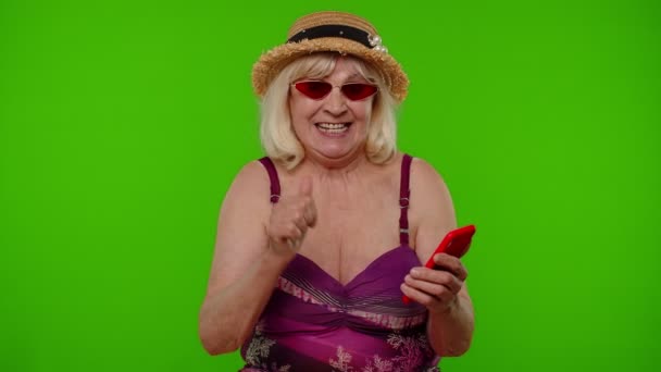 Turista senior en gafas de sol con teléfono móvil celebrando vacaciones vacacionales ganadoras — Vídeo de stock