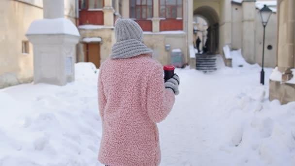 Vrouw reiziger wandelen met warme drank in papieren beker buiten in de stad besneeuwde straat, vakantie vakanties — Stockvideo