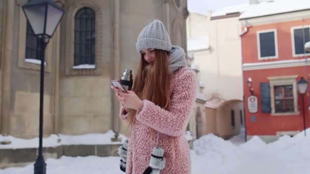 Viajero mujer sosteniendo el teléfono móvil, charlando con amigos y familiares, beber té de bebida caliente — Vídeo de stock