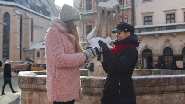 Två leende kvinnor turister reser tillsammans, dricker varmt te, kaffe från termos på stadens gata — Stockvideo