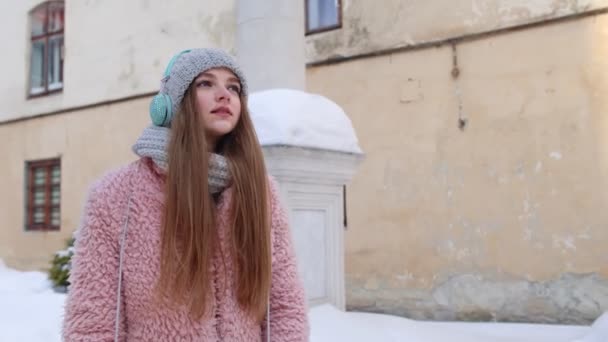 Młoda kobieta podróżuje ulicą miasta i słucha pozytywnych piosenek podcast — Wideo stockowe