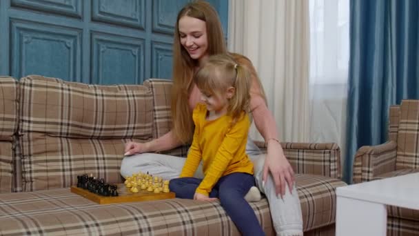 Pequeno bonito filha criança e jovem mãe jogar xadrez em casa sofá, lazer atividades hobbies — Vídeo de Stock