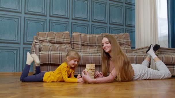 Gelukkig jong moeder vrouw onderwijs klein kind dochter spelen houten blokken bordspel thuis — Stockvideo