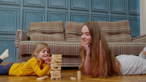 Feliz jovem mãe mulher ensinando criança pequena filha jogando blocos de madeira jogo de tabuleiro em casa — Vídeo de Stock