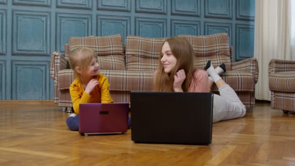 Femme nounou et enfant fille étudier avec ordinateur portable, tout en étant couché sur le sol chaud à la maison — Video