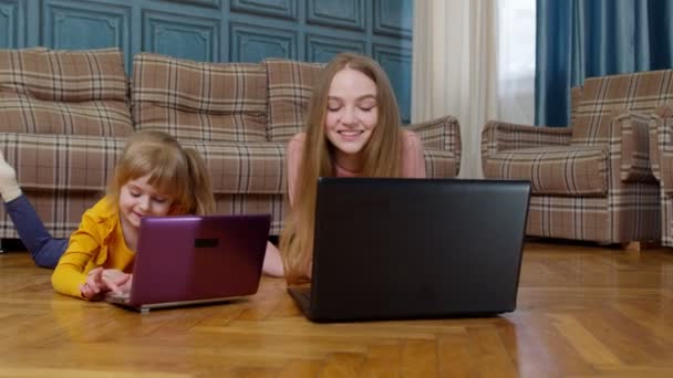 Ibu dan anak kecil duduk di lantai kayu yang hangat di rumah mengerjakan laptop, menonton kartun — Stok Video