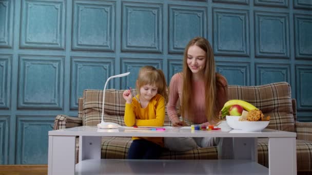 Mooie moeder babysitter leraar helpen kind dochter met huiswerk, leren schrijven thuis — Stockvideo