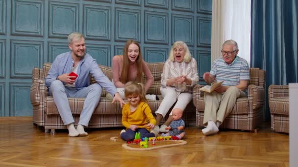 Ocio familiar multigeneracional en el hogar, motivando gritos a niño niña jugando juguete ferroviario — Vídeo de stock