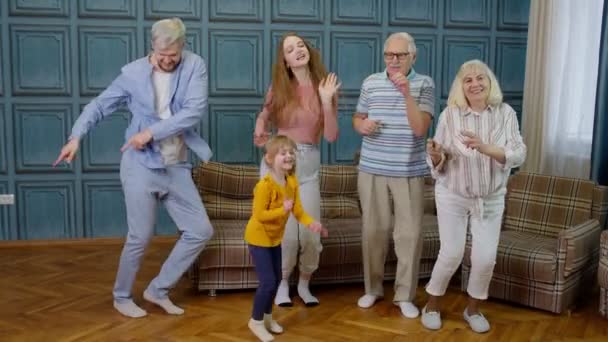 Familieleden van verschillende generaties die plezier hebben met muziek luisteren, gek dansen in de kamer thuis — Stockvideo