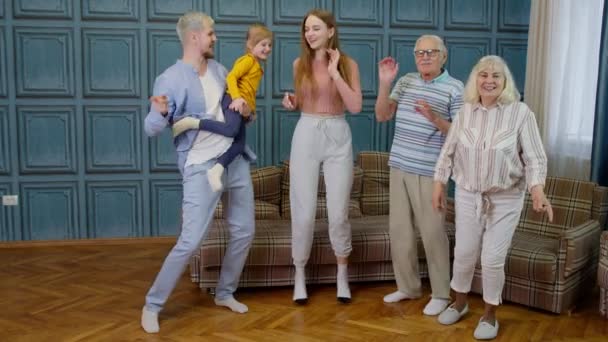 Miembros de la familia de diferentes generaciones que se divierten escuchando música, bailando locos en la habitación en casa — Vídeo de stock