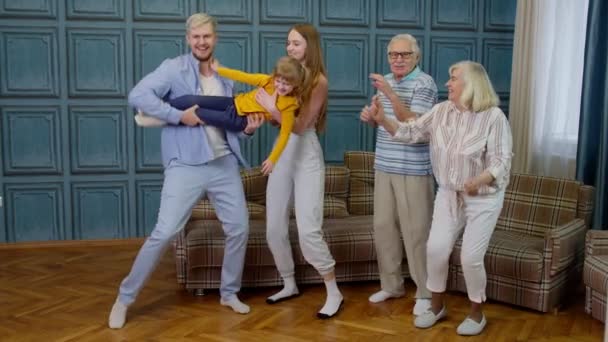 Miembros de la familia de diferentes generaciones que se divierten escuchando música, bailando locos en la habitación en casa — Vídeo de stock