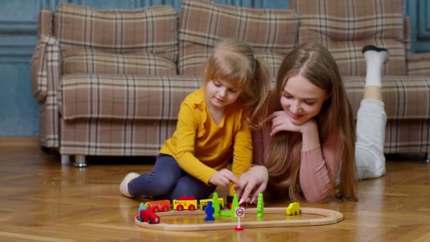 Mãe brincando com criança criança filha montando brinquedo trem na ferrovia de madeira bloqueia jogo de tabuleiro em casa — Vídeo de Stock