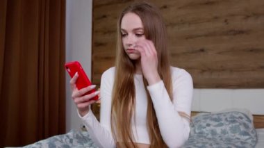 Yoğunlaşmış kadın cep telefonu kullanıyor, internetteki ürünlere bakıyor, yavaşça geziniyor, internette sörf yapıyor.