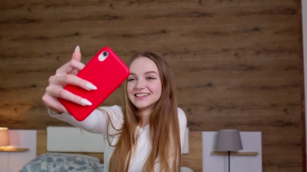 Mujer joven bloguera posando, tomando foto selfie en el teléfono móvil para las redes sociales en la cama en casa — Vídeos de Stock