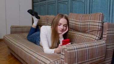 Kız cep telefonu ekranına bakar başarılı online sipariş verir, gülümser ve kameraya bakar.