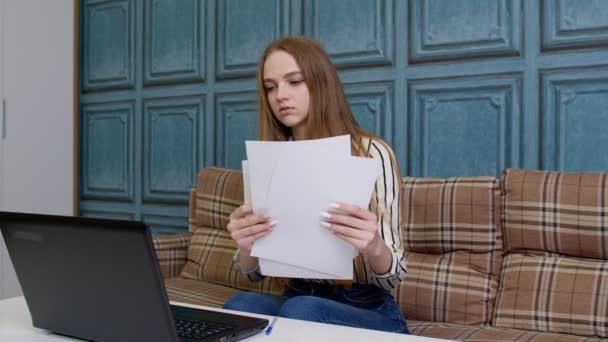 Kobieta siedząca w domu i przeglądająca dokumenty analizuje dokumenty pracujące na laptopie — Wideo stockowe