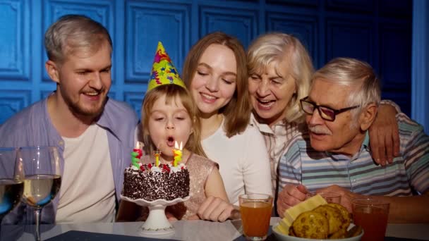 Дівчина святкує день народження з батьками, сім'я старших бабусь і дідусів вибухає свічками на торт — стокове відео
