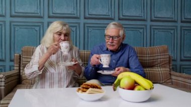 Son sınıf çifti çay içerek konuşuyor, gülüyor, gülüyor, öpüşüyor, evdeki kanepede oturuyor.