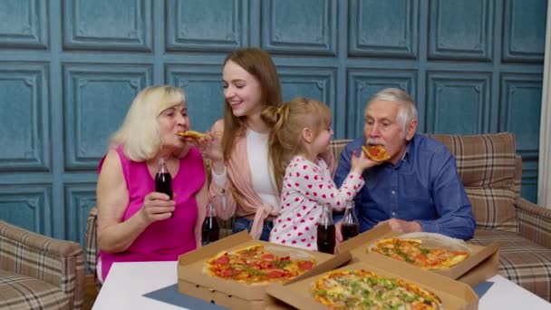 Familia almorzando, alimentándose con pizza, riéndose, disfrutando de la comida juntos en casa — Vídeo de stock