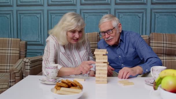 Senior couple grandfather, grandmother resting on sofa, playing game with wooden blocks at home — Stock Video