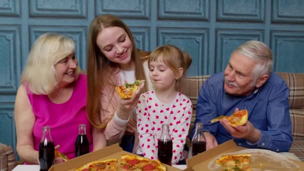 Wielopokoleniowa rodzina je obiad, karmi dziewczynkę pizzą, śmieje się, delektuje posiłkiem — Wideo stockowe