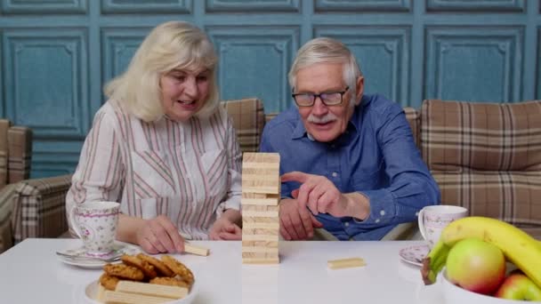 Senior par farfar, mormor vilar på soffan, leka spel med träklossar hemma — Stockvideo