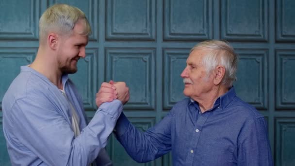 Joven alegre emocionado abrazando viejo padre o abuelo de pelo gris, familia de generaciones masculinas — Vídeo de stock